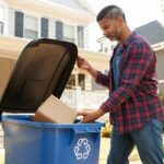 Man putting cardboard box in recycling bin
